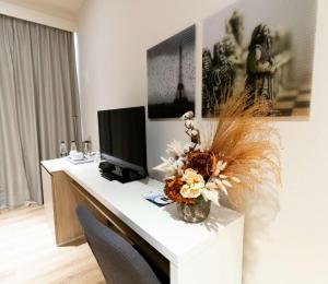 a desk with a computer and a vase of flowers on it at Best Western Premier Ark Hotel in Tirana