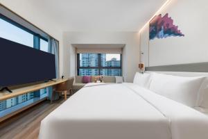 Habitación de hotel con cama grande y TV de pantalla plana. en Elong Hotel Shenzhen South China City, en Shenzhen