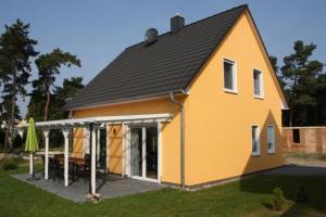 duży żółty dom ze stołem na dziedzińcu w obiekcie K 99 - Ferienhaus mit Kamin & WLAN in Röbel an der Müritz w mieście Röbel