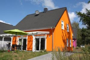 an orange house with an umbrella in front of it at K 105 - Ferienhaus für die ganze Familie mit Kamin in Röbel an der Müritz in Röbel