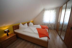 a bedroom with a bed with white and orange pillows at K 105 - Ferienhaus für die ganze Familie mit Kamin in Röbel an der Müritz in Röbel