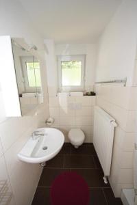 a white bathroom with a sink and a toilet at K 94 - Stilvolles Ferienhaus mit Kamin in Roebel an der Mueritz in Marienfelde