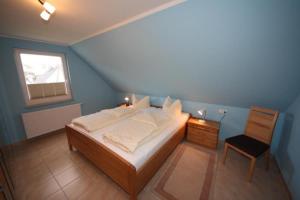 a blue bedroom with a bed and a chair at K77 - 5 Sterne Ferienhaus mit Sauna, grossem Garten direkt am See in Roebel an der Mueritz in Marienfelde