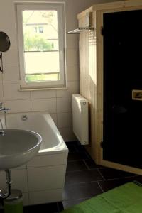 ein Bad mit einer Badewanne, einem Waschbecken und einem Fenster in der Unterkunft K 104 EG - moderne Ferienwohnung am See mit Sauna & Kamin in Marienfelde