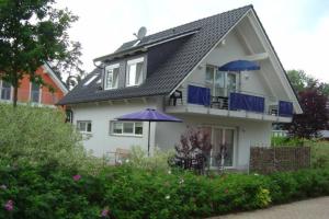 una casa blanca con dos sombrillas azules delante en 44 EG - Ferienwohnung mit Terrasse und Seeblick, en Röbel