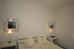 a white room with a bed and two lamps at 44 EG - Ferienwohnung mit Terrasse und Seeblick in Röbel