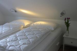 białe łóżko z 2 poduszkami i wazonem z kwiatami w obiekcie K 104 OG - stilvolle Ferienwohnung am See mit Balkon & Sauna in Röbel an der Müritz w mieście Marienfelde