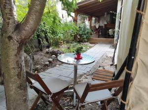 un patio con mesa, sillas y un árbol en Glamping Casa Soarelui, en Vama Veche