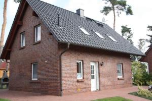 een rood bakstenen huis met een zwart dak bij 26 - Schoenes Ferienhaus mit Kamin fьr die ganze Familie direkt am See in Roebel in Röbel