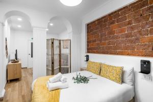 a bedroom with a white bed and a brick wall at Charming Chueca Center in Madrid