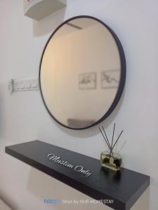 uno specchio su una mensola nera con un orologio sopra di Nur’s Homestay a Kuala Kelawang