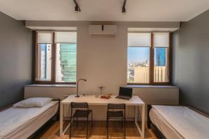 a room with a desk with a laptop and two beds at Kantar Hostel in Yerevan