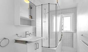 La salle de bains blanche est pourvue d'un lavabo et d'une douche. dans l'établissement Odinn Reykjavik Eiriksgata Apartments, à Reykjavik