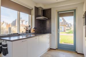 a kitchen with a sink and a large window at Dormio Villapark Duynzicht in Julianadorp