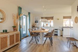 una cucina e una sala da pranzo con tavolo e sedie di Dormio Villapark Duynzicht a Julianadorp