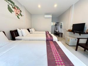 a hotel room with two beds and a television at Be Leaf Resort SHA in Thalang