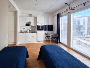 een kamer met 2 bedden en een keuken met een raam bij Studio next to train station, 7 mins by train to airport in Vantaa