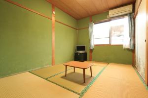 a room with a table and a tv in it at Miyanouraso in Yakushima