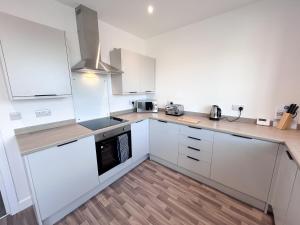 a kitchen with white cabinets and a stove top oven at High Market Place by Blue Skies Stays in Ashington