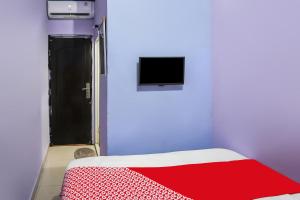 Cette chambre comprend un lit avec une couverture rouge et une télévision. dans l'établissement OYO 93772 Iconiq Rooms, à Bekasi