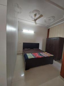 1 dormitorio con 1 cama y ventilador de techo en Shri Achyutam Villa en Vrindāvan