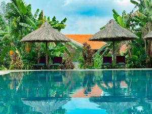 a resort swimming pool with umbrellas and chairs at Hue Ecolodge in Hue