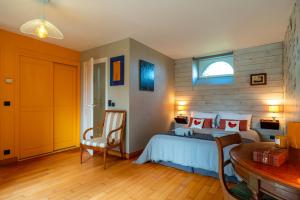 a bedroom with a bed and a chair and a window at Le Relais - Maison avec grand jardin in Bannalec