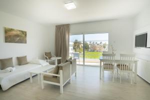 a living room with a couch and a table and chairs at Liquid Hotel Apartments in Ayia Napa