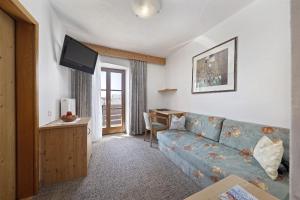 sala de estar con sofá azul y escritorio en Garni-Hotel Tritscherhof, en Tirolo