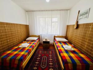 two twin beds in a room with a window at Dadow Cozy House in Naryn