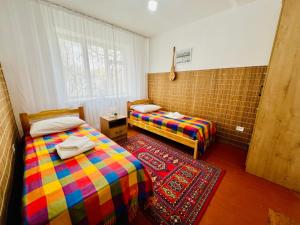 a room with two beds and a rug at Dadow Cozy House in Naryn