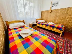 two beds in a room with a colorful blanket at DADOW Apartments in Naryn
