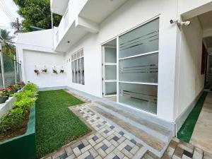 a modern house with white walls and a garden at The Hostel in Gampaha