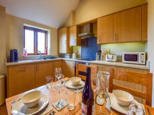 una cocina con una mesa con copas y una botella de vino en The Brambling en Bidford