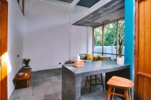 a kitchen with a counter and a table with stools at Loji Nyanyi in Tanah Lot