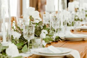 een houten tafel met glazen en witte bloemen erop bij Domaine Les Jardins dArsene in Tinténiac