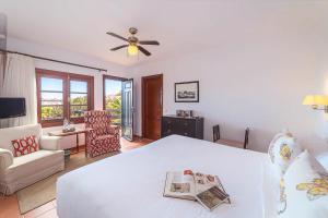 a bedroom with a white bed with a ceiling fan at Hotel EL GRIFO in San Bartolomé