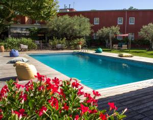 a swimming pool with red flowers in front of a building at Best Western Plus Le Lavarin Avignon in Avignon