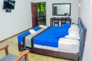 a bedroom with a large bed with blue sheets at ShiCo Transit Hotel in Negombo