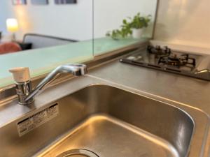 OUCHI HOTEL Hatchobori في هيروشيما: يوجد حوض مطبخ حديد قابل للصدأ في المطبخ