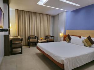 um quarto com uma grande cama branca e uma cadeira em Hotel Daaysco Oley Allo em Guwahati