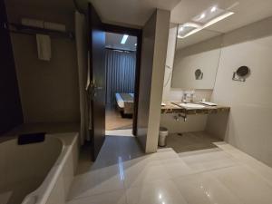 uma casa de banho com uma banheira, um lavatório e um espelho. em Hotel Daaysco Oley Allo em Guwahati
