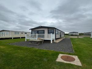 a tiny house with a porch and a bench at Lovely 2-Bed Caravan in Prestonpans in Longniddry