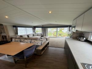 ein Wohnzimmer mit einem Sofa und einem Tisch in der Unterkunft Lovely 2-Bed Caravan in Prestonpans in Longniddry