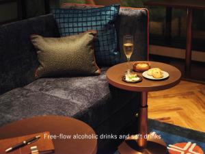 فندق ميتسوي غاردن أوساكا بريميير في أوساكا: طاولة مع كوب من النبيذ على أريكة