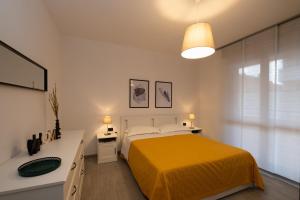 a white bedroom with a yellow bed and a sink at Bilocale a Lainate LainHouse in Lainate