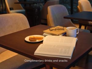 a table with a book and a cup of coffee and a plate of food at Mitsui Garden Hotel Osaka Premier in Osaka