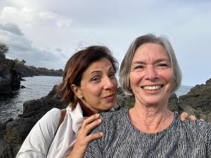 dos mujeres de pie en rocas cerca del agua en Adriana casa vacanze mare Etna Sicilia, en Acireale