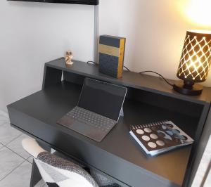escritorio con ordenador portátil, lámpara y mando a distancia en SWEET APPARTMENT, en Patra