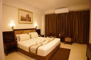 a hotel room with a large bed with white pillows at Fu Wang Dominous Resort in Cox's Bazar